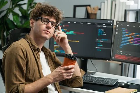 IT worker looking at camera holding coffee cup at modern office. Gusher. Foto stock