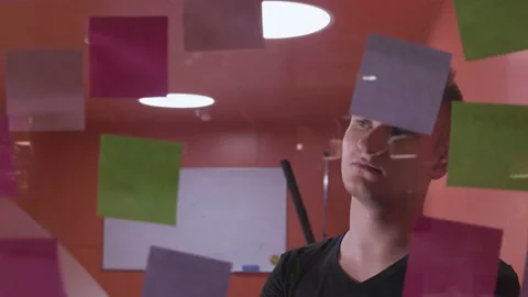 IT worker tracking his tasks on board. Man attaching sticky note to task board Stock Footage 141667741