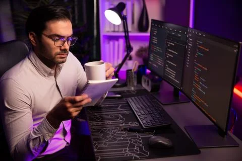 IT working with drinking coffee coding on pc screen, reading note. Surmise. Stock Photos