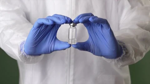 It works. Lab assistant in personal protective equipment holding a vial of new Stock Footage 147961298