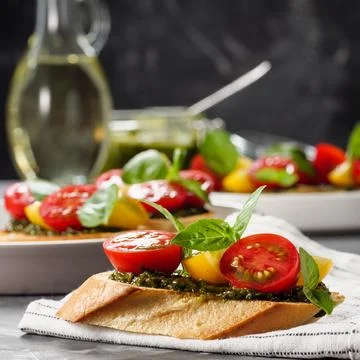 Italian antipasti bruschetta with tomato, basil and pesto on a gray table. Co Stock Photos