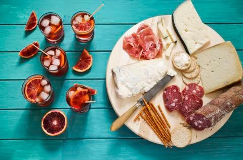An Italian appetiser platter next to glasses of aperitifs garnished with slices Stock Photos