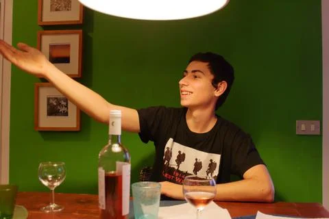 An Italian boy gesticulates while talking to friends at a table drinking wine Stock Photos