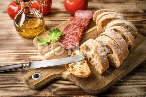Italian ciabatta bread cut in slices with salami. Stock Photos