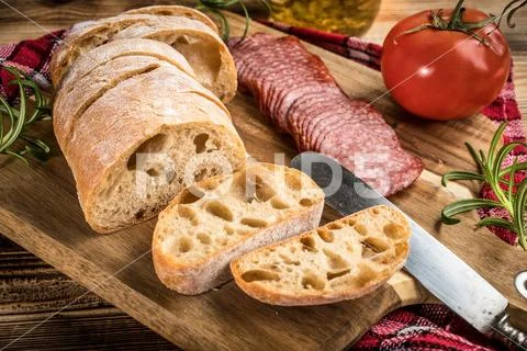 Italian ciabatta bread cut in slices with salami. Stock Photos