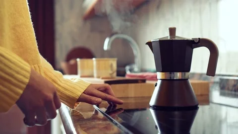 Italian coffee pot boiling on the kitchen. A girl stops it and prepares it 스톡 동영상 130867047