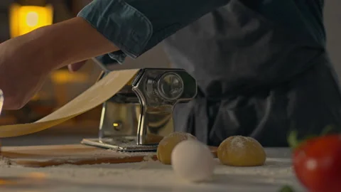 Italian, cooking master immersed Rolls out the dough with a roller press In Stock Footage 245806672