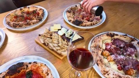 Italian Dinner Table with Neapolitan Pizza Red Wine and Cheese Board Stock Footage 338420118