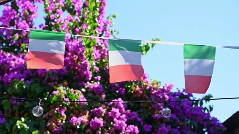 Italian flags fluttering on string above flowering garden patio Stock Footage 345080306