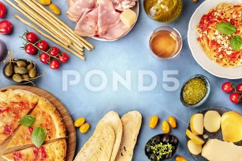 Italian food background. Pizza, pasta, cheese, hams, wine, olives, pesto, capers Stock Photos