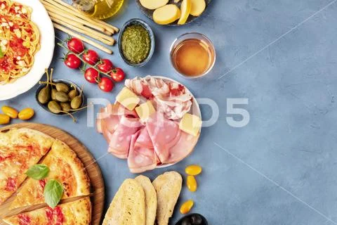 Italian food background. Pizza, pasta, cheese, hams, wine, pesto and capers Stock Photos