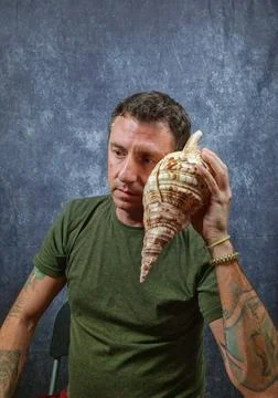 Italian man hears a large shell coming up to his ear Foto stock