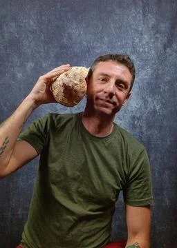 Italian man hears a large shell coming up to his ear Stock Photos