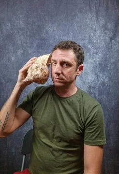 Italian man hears a large shell coming up to his ear Stock Photos