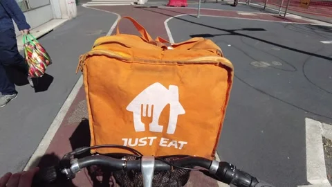 Italy , Milan 2023 - Uber eats delivery food - bike rider going in a street with Stock Footage 237360529