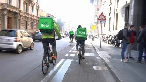 Italy , Milan January 21,2020 - Uber eats delivery food - bike driver going in a Stock Footage