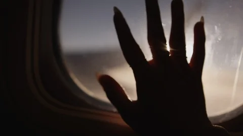 Italy package 5 | Light rays shining through hand fingers in airplane window Stock Footage 115968065