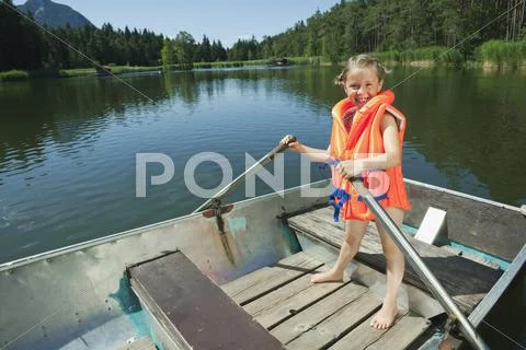 Italy, South Tyrol, Girl (6-7) standing in rowing boat, smiling, portrait Stock Photos