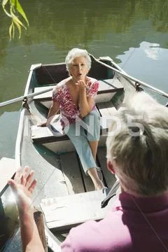 Italy, South Tyrol, Senior couple in rowing boat, senior woman blowing a kiss, Stock Photos