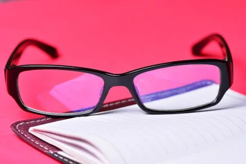 Items freelancer on a red background. Glasses and notebook Stock Photos
