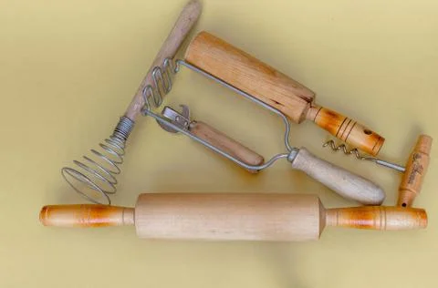 Items of kitchen utensils: a rolling pin, press for mashed potatoes, egg beater Stock Photos