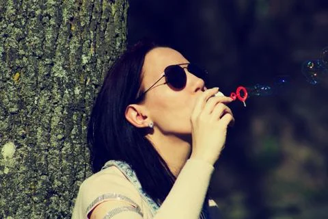 IThe young woman has bubble blower and she blows bubbles Stock Photos