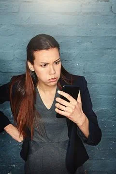 Its about time for a phone upgrade. an angry businesswoman looking at her phone Stock Photos