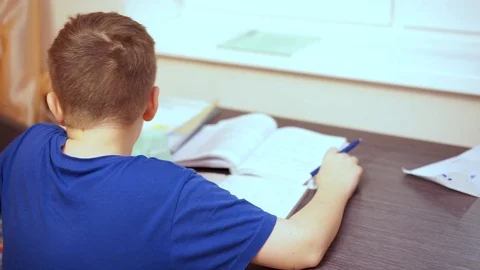 It’s boring for a boy to sit at a table and perform a school assignment. 스톡 동영상 99468293