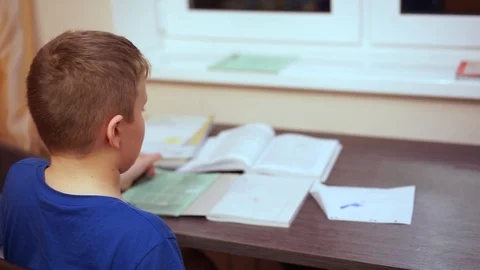 It’s boring for a boy to sit at a table and perform a school assignment. 스톡 동영상 99468341
