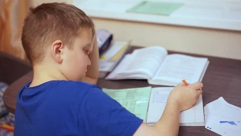 It’s boring for a boy to sit at a table and perform a school assignment. Video stock 99468387