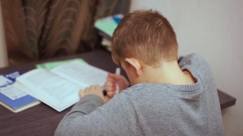 It’s boring for a boy to sit at a table and perform a school assignment. Video stock 99468432