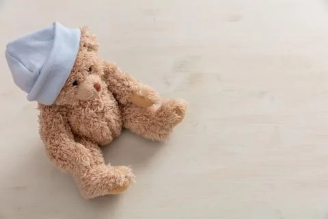 It's a boy concept. Teddy bear wearing pastel blue cap on wooden background, Stock-Fotos