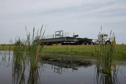 With its image reflected in the water, a heavy load transport truck procee... Fotos de archivo