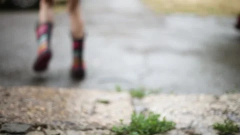 It's raining children walk under umbrellas in rubber boots Stock Footage 142707802