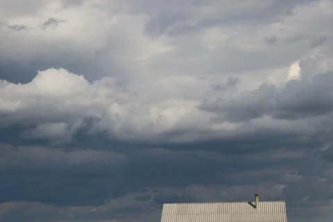 It's raining Dark rain clouds are gathering over the roof of a house in the Foto stock