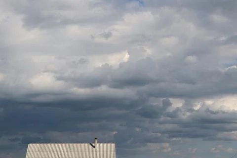 It's raining Dark rain clouds are gathering over the roof of a house in the Stock Photos