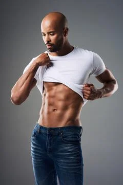 Its a sin wearing a shirt over these abs. a handsome young man taking off his t Stock Photos