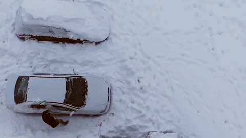 It's snowing in a city and a person is clearing the roads with a shovel, Stock Footage 168988853