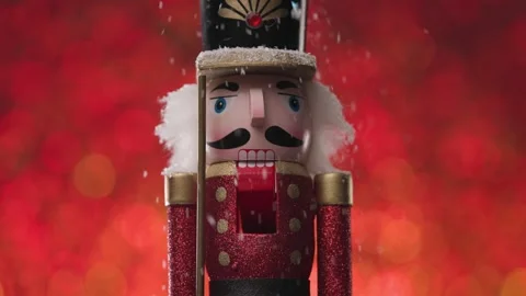 It's snowing on the Nutcracker, closeup framing it's face, on bright red and Stock Footage 321679899