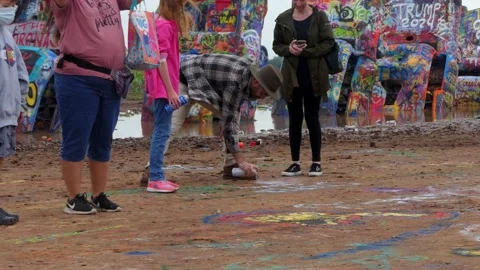 It's so muddy at the Cadillac Ranch that families are spray painting the ground 動画素材 195280132