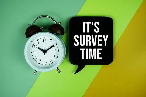 It's Survey Time text on speech bubble with alarm clock top view on green a.. Stock Photos