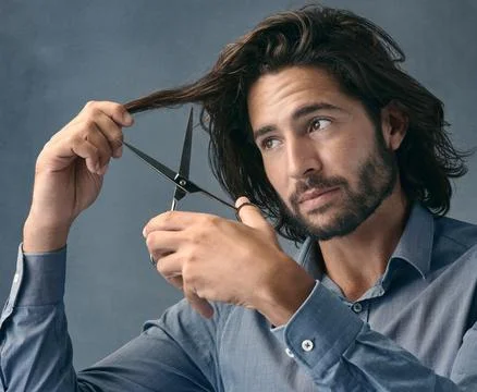 Its time to chop it all off. Studio shot of a handsome young man cutting his Stock-Fotos