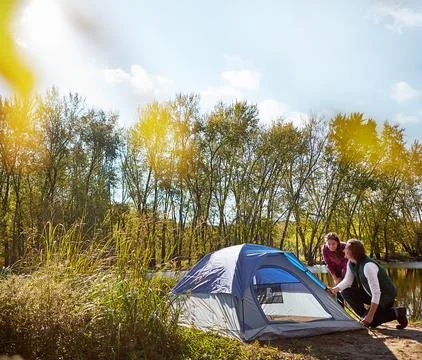 Its time to elevate your camping game. an adventurous setting up their tent by Stock Photos