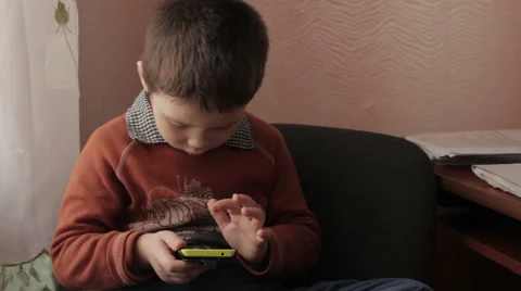 Ittle boy playing a game on your smartphone Stock Footage 59181836