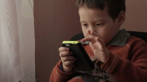 Ittle boy playing a game on your phone Stock Footage 59301775
