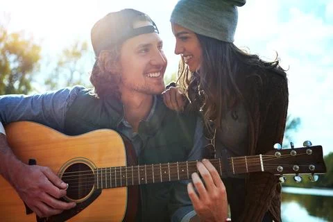 Ive been waiting so long to tell you. a young man playing his girlfriend a song Stock Photos
