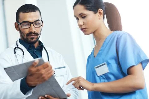 Ive noticed an irregularity here. two young doctors using a digital tablet in a Stock Photos