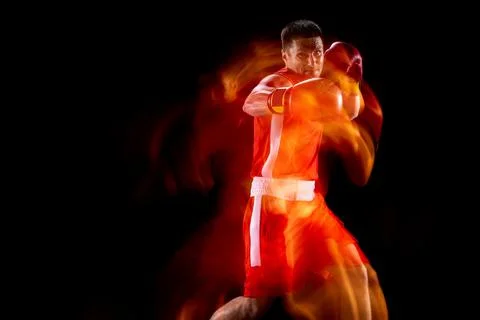 Jab, hook. Portrait of professional male boxer in motion, action on black studio Stock Photos