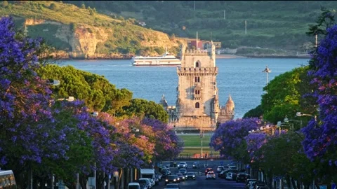 Jacaranda trees bloom by Belem Tower at sunset in Lisbon Portugal Stock Footage 344956238