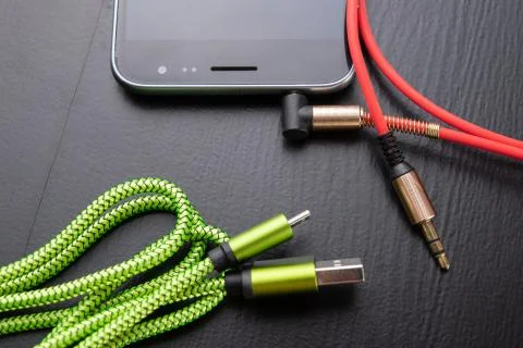 Jack and usb cable for smartphone. Telephone and accessories on the table. Stock Photos
